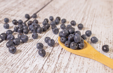 Fresh sweet blueberry fruit in wooden spoon. Dessert healthy food. Group of ripe blue juicy organic berries.