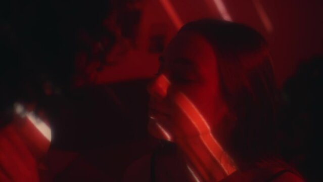 Sensual partners kissing and caressing each other in dark bedroom with red light projection