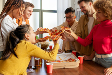 multiracial group of young people at a house party ordered pizza and beer