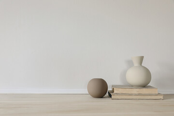 Set of modern brown and beige ceramic vases of geometric shapes on wooden table. Old books. White...