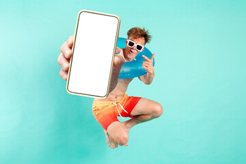 young cheerful guy winner with inflatable swim ring jumps and shows blank smartphone screen