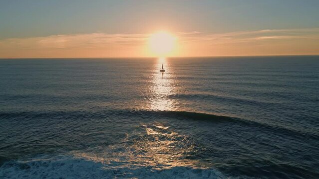 Silhouette sailing boat sunset aerial view. Sun reflecting in beautiful ocean