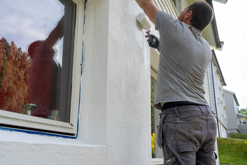 Man With Paint Roller Applying Cement Based Putty: Wall Renovation Process.