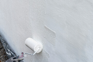 Man Plasters Wall: Using Paint Roller for Smooth Application and Finish.