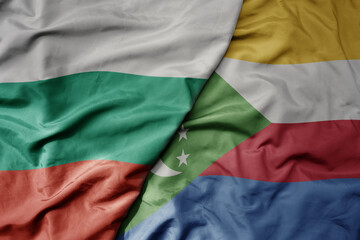big waving national colorful flag of comoros and national flag of bulgaria .