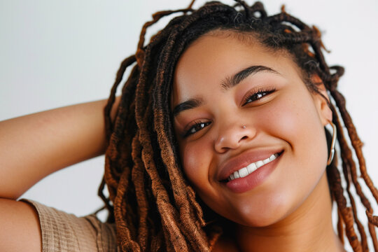 Close up portrait of beautiful curvy African American woman with dreadlocks smiling at camera over white background