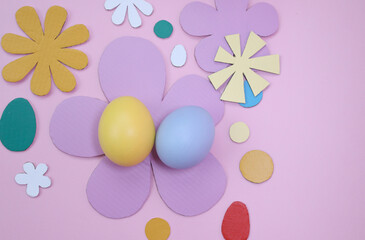 Easter decoration with colored eggs and paper flowers on pink background 