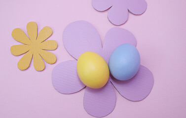 Easter decoration with easter eggs and paper flowers on pink background 