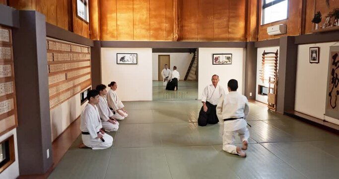 Black belt students, karate or master teaching martial arts in dojo for aikido, movement or self defense. Combat demonstration, Japanese people or training workout for fighting, education or class
