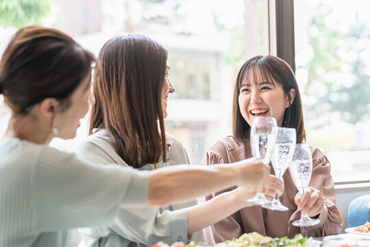 女子会でレストラン・カフェ・飲食店でシャンパンを持って乾杯する女性達（アジア人）
