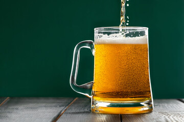 Beer is pouring into a mug on a green background. Celebrating St. Patrick's Day. Traditional Irish...