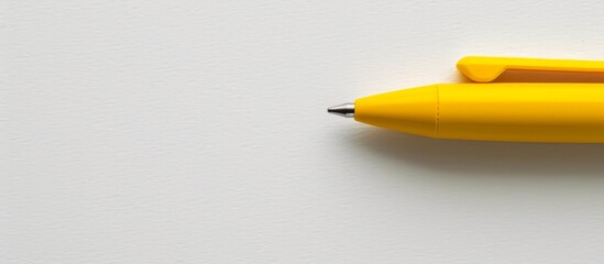 Vivid yellow pen with a sleek black tip placed on a clean white desk surface
