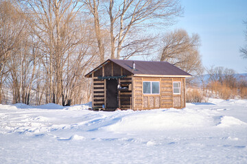 Russian wooden bath in winter. The fallen white snow lies on the ground.