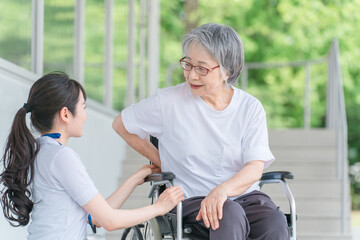 車椅子に乗る腰痛が治った笑顔の高齢者と介護士の女性
