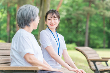 公園で話す高齢者と笑顔の介護スタッフの女性(話す・楽しい)
