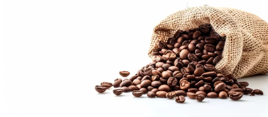 Fotobehang Aromatic coffee beans spilling out of a rustic sack on a wooden table © AkuAku