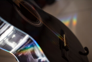 Música. Cuerdas de Güitarra negra acustica de lado, coloreadas con rayo de luz multicolor.