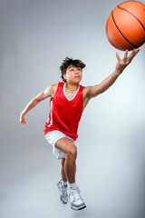 Young male basketball player jumping to make a layup shot play