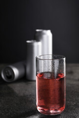 Energy drink in glass and aluminium cans on grey table