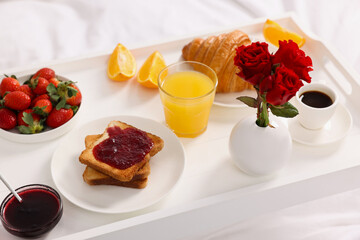 Tray with delicious breakfast on bed, closeup