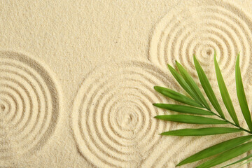 Fototapeta na wymiar Zen rock garden. Circle patterns and green leaf on beige sand, top view