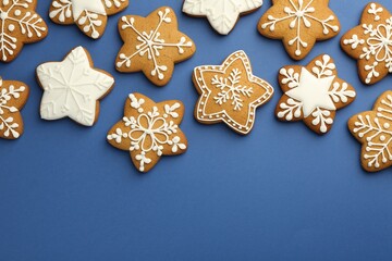 Tasty star shaped Christmas cookies with icing on blue background, flat lay. Space for text