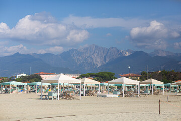 Fototapeta na wymiar Beach with umbrellas and mountains. Tuscany. Marina di Pietrasanta