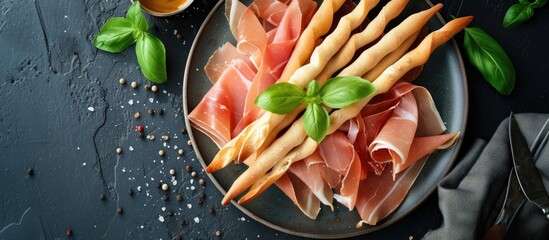 A top view of a plate featuring savory prosciutto ham adorned with fresh basil leaves. - obrazy, fototapety, plakaty