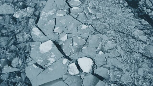 Flying over thick ice on top of a frozen lake during the middle of winter.
