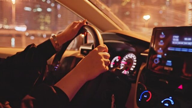 Successful woman driving premium class car in night city, hands close-up.