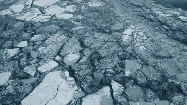 Flying over thick ice on top of a frozen lake during the middle of winter.