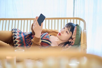 寝ながらスマートフォンを見る女性