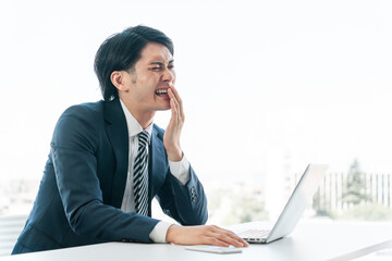 唇の乾燥・口内炎・虫歯・痛みで悩むデスクワークをしている若いアジア人男性ビジネスマン  © buritora