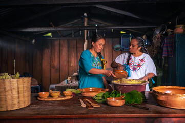 Two Latin women talk while making a delicious handmade dessert made with spices, corn kernels and...