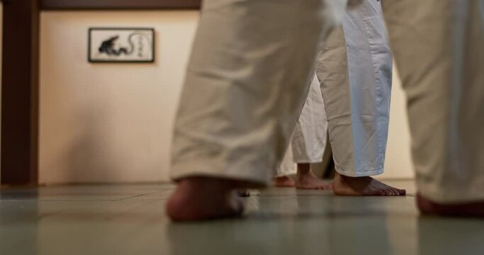 Students, legs or learning martial arts in dojo for practice, aikido movement or self defense together. Combat demonstration, people or closeup of feet in training for fighting, education or class