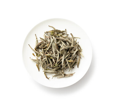 Some dried tea buds in a white porcelain dish. White tea sample.
