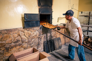 Baker removes cookies already baked in a traditional oven from the oven.