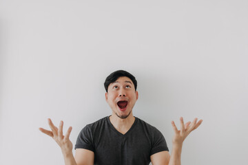 Headshot of shock face asian man in black t-shirt stand isolated on white wall.