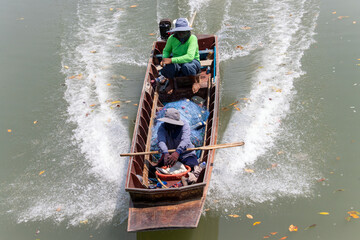 A couple rides a boat with fishing net in a water canal on the outskirts of Bangkok, Thailand