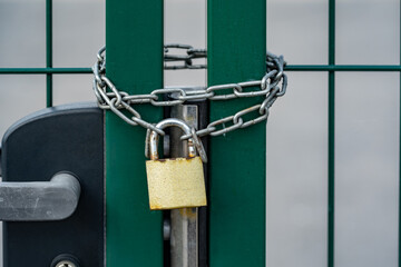 Green gate secured with a strong chain and a generic padlock, object closeup. Security and safety...