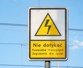 Caution sign with a warning message in Polish against touching overhead electrical wiring...