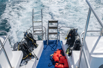 Diving equipment with oxigen tanks and fins sitting at the back of the tour boat. Active vacation,...