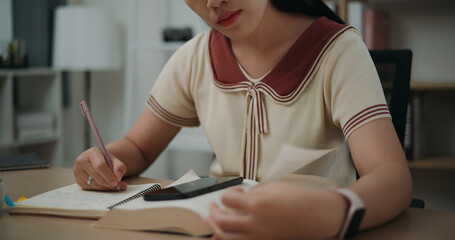 Selective focus, Hands of Female writer sitting at desk writing information on diary notebook while...