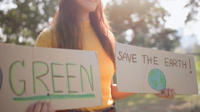 Go green people young woman hand raised showing save the earth planet world care banner poster sign in city nature tree sun light sunset. Plastic free issues Protect future asian hope net zero waste
