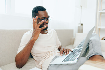 Smiling African American Freelancer Typing on Laptop in Modern Home Office A young African American...