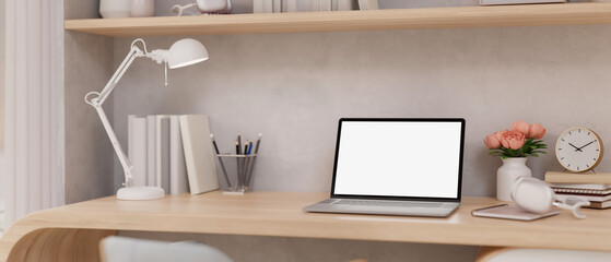 A minimal Scandinavian beige home office workspace with a laptop mockup and decor on a wooden table.