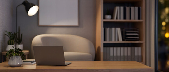 A laptop computer on a wooden coffee table in a modern cozy living room or home office at night.