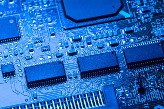 computer circuit board with chips and different electronic components. toned blue. closeup view.