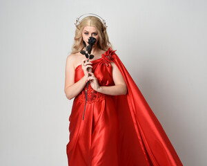 Close up portrait of beautiful blonde model wearing flowing red silk toga gown and crown, dressed...