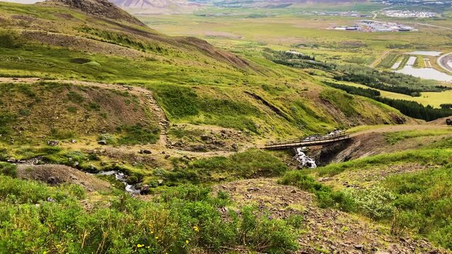 Small wooden hiking trail bridge over mountain stream in Iceland, panning view